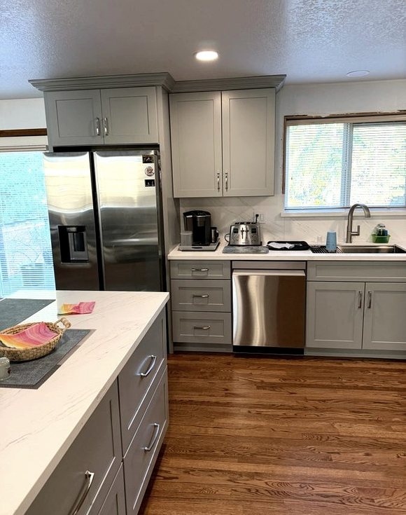 A kitchen remodelled by DA Interior Solutions: grey shaker cabinets, a quartz island and oak floors